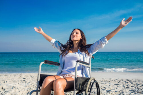 mujer en silla de ruedas en la playa gracias al turismo accesible